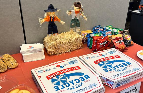 Pizzas, cookies and chips on a table with a miniature scarecrows and fall theme.